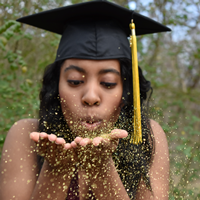 woman graduate blowing gold confetti