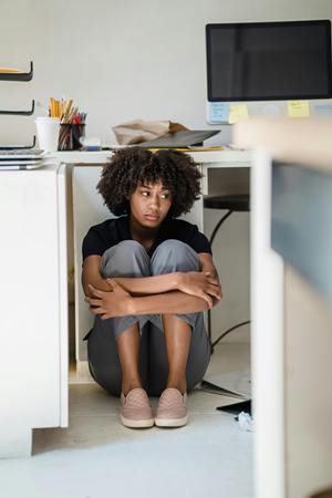 woman hiding under desk