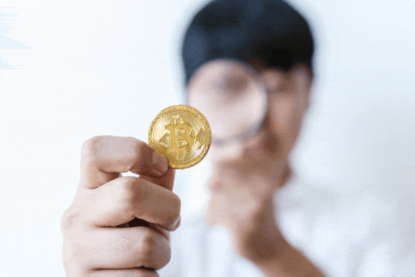 man studying a physical token through a magnifying glass